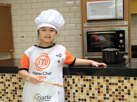 Aluna do Criarte na cozinha pedagógica, de touca de chef