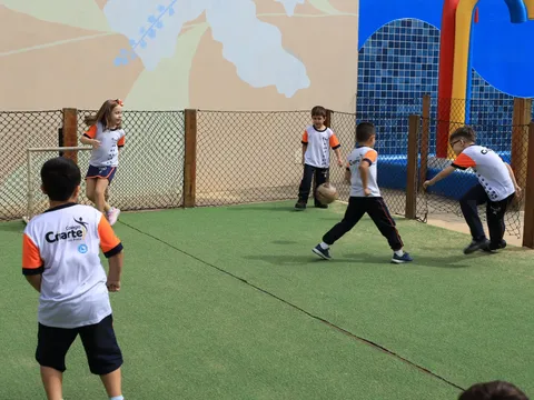 Alunos do Criarte jogando futsal no gramado sintético