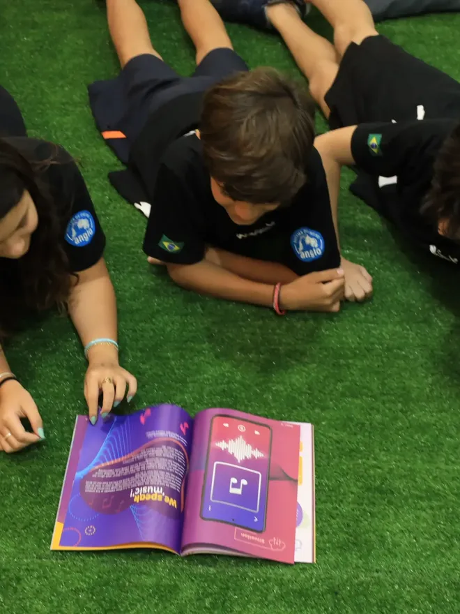 Alunos do Fundamental II do Criarte lendo o material bilíngue no gramado